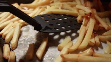 Patates kızartmasını fırında pişirme tepsisinde karıştırmaya yakın çekim. Evde ya da restoranda yemek pişirmek. Fast food, sağlıksız beslenme.