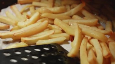 Patates kızartmasını spatulayla karıştırıp ters çevirmeye yakın çekim. Fast food, sağlıklı beslenme, fırında pişirme.