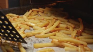 Patates kızartmasını fırında kızartma tavasında karıştırmaya yakın çekim. Fast food, sağlıklı beslenme, fırında pişirme.