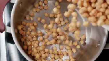 Haşlanmadan ve pişirilmeden önce metal tavaya dökülen çiğ bezelyelerin yavaş çekimleri. Arap, Türk, Doğu mutfağı.