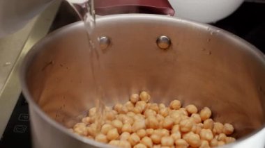 Nohutla birlikte tencereye sıcak su dökmeye yakın. Baklagil pişirme, sağlıklı beslenme, vejetaryen yemekleri.