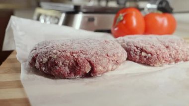 Mutfak masasında elektrikli ızgaranın yanında duran dondurulmuş hamburger köfteleri ve malzemeler.