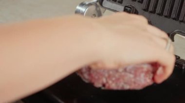 Buzlu hamburger köftelerini ızgaraya koymak için yakın plan. Evde yemek pişirme, mutfak aletleri, sağlıklı beslenme, hamburger malzemeleri.
