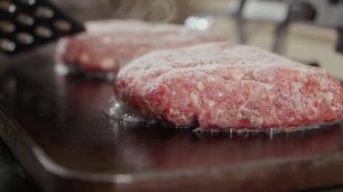 Hamburger köftelerinden akan ve kaynayan meyve suyu. Evde yemek pişirme, mutfak aletleri, sağlıklı beslenme, hamburger malzemeleri.