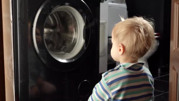 可爱的男婴坐在浴室里 看着工作的洗衣机 做家务和家务活 儿童教育和发展 — 图库视频影像