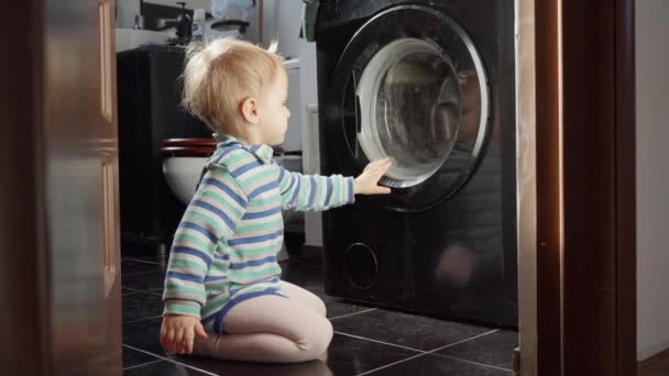 洗濯機の回転ドラムに興味を持って見て小さな赤ちゃんの男の子 子どもの教育 — ストック動画