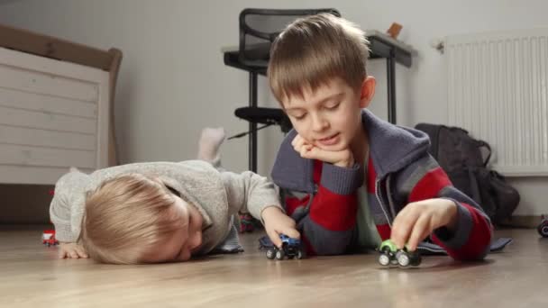 Два Брата Лежат Полу Играют Разноцветными Игрушечными Машинками Дети Играющие — стоковое видео