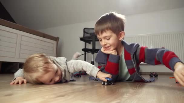 Мальчик Играет Своим Младшим Братом Игрушечными Машинками Полу Спальне Дети — стоковое видео