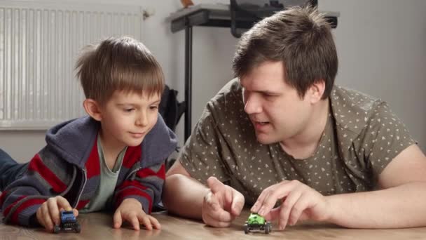 年轻的父亲和男孩在卧室的地板上进行玩具汽车竞赛 儿童独自玩耍 发展和教育 家庭游戏 — 图库视频影像