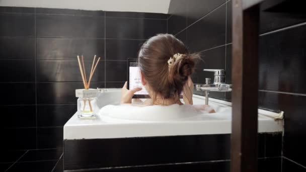 妇女享受泡泡浴的后视镜 并将她的平板电脑用于娱乐 — 图库视频影像