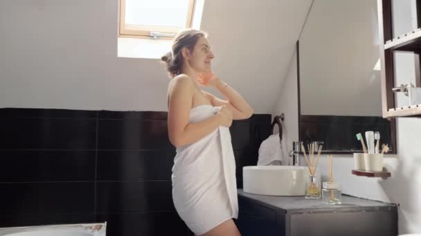 女人裹着毛巾 站在浴池里 看着镜子里的自己 个人卫生和保健做法 — 图库视频影像
