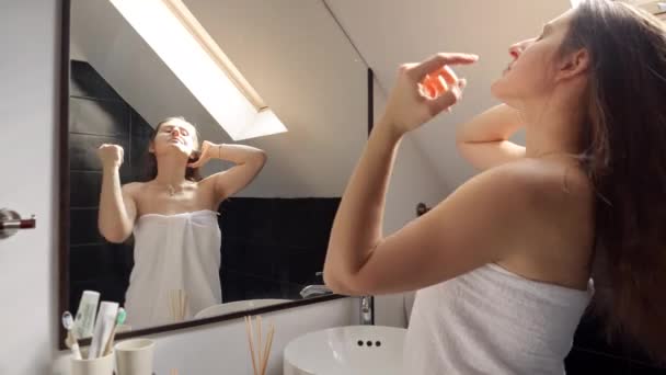 女人站在浴池里 披着毛巾 在镜子里凝视着自己 良好的卫生习惯和自理习惯 — 图库视频影像