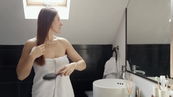 Kobieta Owinięta Ręcznik Stojąca Wannie Pielęgnująca Długie Włosy Przed Lustrem — Wideo stockowe
