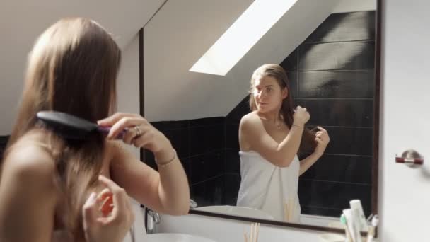 Kobieta Stojąca Wannie Pokryta Ręcznikiem Czesająca Długie Włosy Podziwiając Się — Wideo stockowe