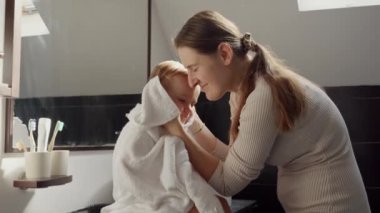 Havluya sarılmış, banyo yaptıktan sonra gülümseyen anne ve bebeğin portresi. Ebeveynlik, mutluluk ve çocuk hijyeni kavramı