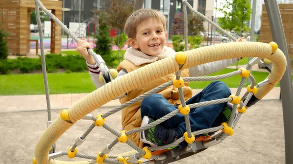 Szczęśliwy Śmiejący Się Chłopiec Bawiący Się Huśtawką Sieci Publicznym Placu — Zdjęcie stockowe