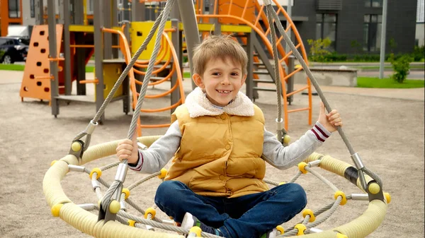 Szczęśliwy Uśmiechnięty Chłopiec Bawiący Się Publicznym Placu Zabaw Wirujący Huśtawce — Zdjęcie stockowe