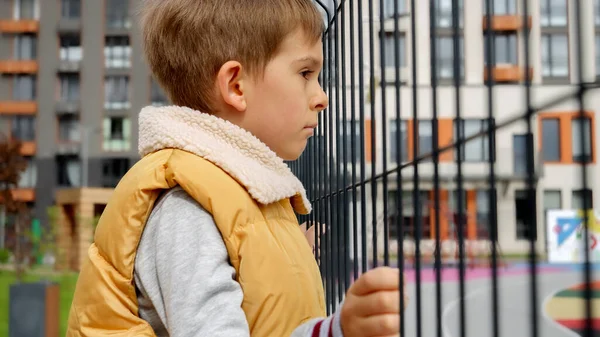 Sad Little Boy Holding Metal Fence Public Playground Looking Child — Stock Photo, Image