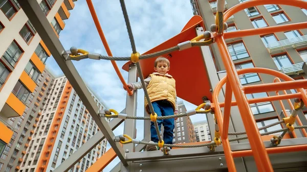 遊び場でロープブリッジを歩いている小さな男の子の地面からの眺め アクティブな子供 スポーツや開発 屋外で遊んでいる子供たち — ストック写真