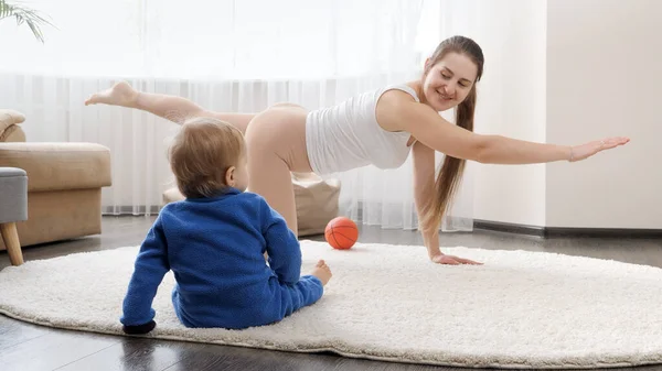 Lindo Niño Sentado Suelo Mirando Madre Haciendo Fitness Yoga Casa —  Fotos de Stock