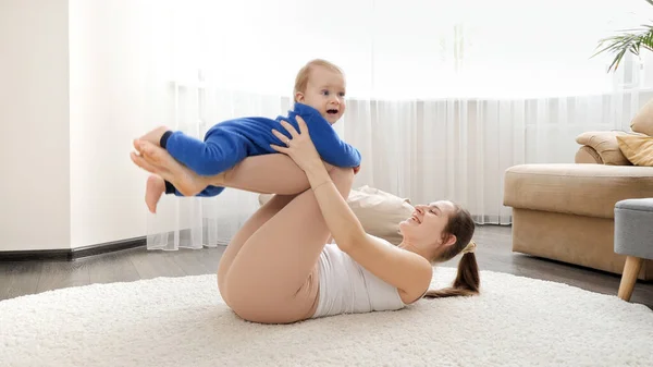 Young Woman Lying Floor Rocking Her Baby Son While Doing — Stock Photo, Image