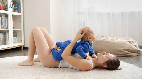 Young Loving Mother Holding Her Baby Son While Doing Fitness — Stock Photo, Image