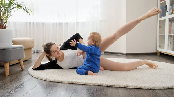 Słodki Chłopiec Oglądając Młodą Matkę Leżącą Podłodze Robi Rozciąganie Ćwiczenia — Zdjęcie stockowe