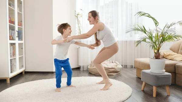 快乐的微笑着的母亲和她的小儿子在客厅里玩耍跳舞 一起玩乐 听音乐 积极的生活方式 养育子女和儿童发展的家庭 — 图库照片
