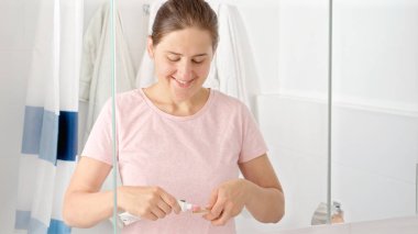 Pijamalı, diş macunu süren ve sabah dişlerini fırçalayan genç bir kadın. Diş sağlığı, ağız kontrolü ve ağız temizliği kavramı