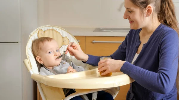 小さな赤ん坊の男の子が台所で椅子に座って朝食を取っている 子育て 健康的な栄養とベビーケアの概念 — ストック写真
