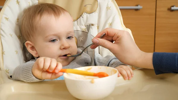 Closeup Portrait Baby Boy Holding Spoon While Mother Feeding Him — Stock Photo, Image