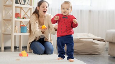 Genç bir anne oğluna yürümeyi öğretiyor. Bebek gelişimi, çocuk oyunları, eğitim ve öğrenim