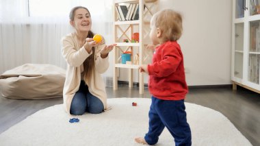 Mutlu anne, küçük oğluna gülerek evde ilk adımlarını atıyor. Bebek gelişimi, aile oyunları, ilk adımlar, ebeveynlik ve bakım.
