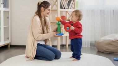 Annesiyle oyuncak kulesi kuran ve oyuncaklarla oynayan küçük bir çocuk..