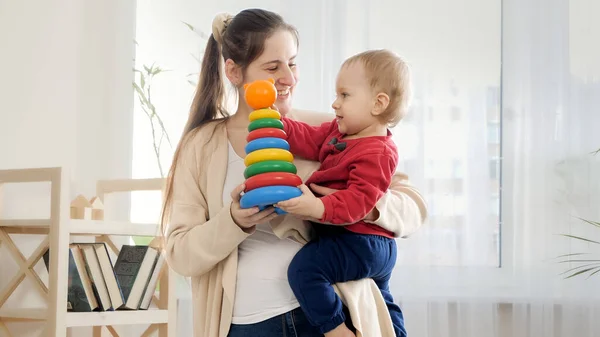 Sorridente Madre Tenendo Suo Seno Bambino Dandogli Colorato Torre Giocattolo — Foto Stock