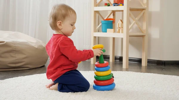 小男孩在客厅的地毯上玩五颜六色的玩具金字塔 婴儿发育 家庭游戏 迈出第一步 养育和照料 — 图库照片