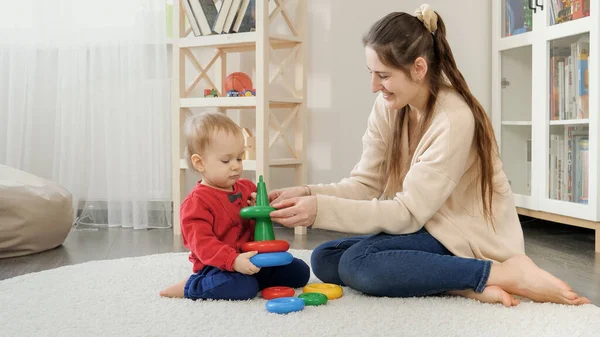 Młoda Kochająca Matka Pomaga Synowi Złożyć Kolorowe Wieże Zabawki Lub — Zdjęcie stockowe