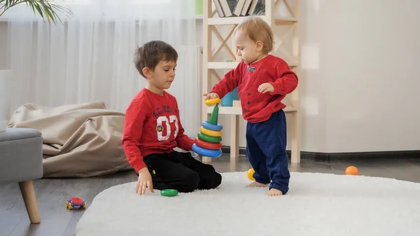 小男孩和他哥哥在客厅里组装五彩缤纷的玩具金字塔 儿童教育 婴儿发展 家庭游戏的概念 — 图库照片