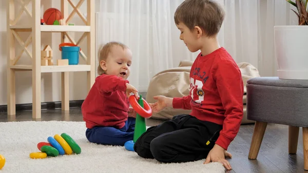 哥哥在客厅的地板上教小男孩组装五颜六色的玩具塔 儿童教育 婴儿发展 家庭游戏的概念 — 图库照片