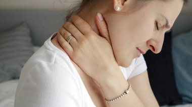 Boynuna masaj yapan ve acı çeken genç bir kadın. Sağlık sorunları, ağrı kesici ve yaralanma kavramı