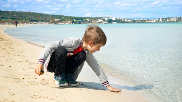Menino Sentado Praia Areia Tocando Mar Frio Depois Com Mão — Fotografia de Stock