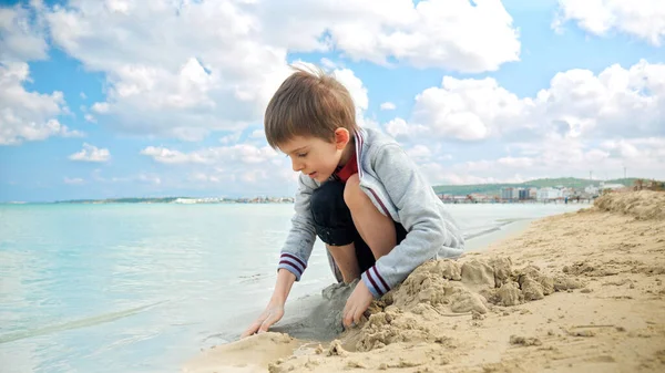 Ένα Χαρούμενο Αγόρι Παίζει Δίπλα Στον Ωκεανό Απολαμβάνοντας Την Άμμο — Φωτογραφία Αρχείου