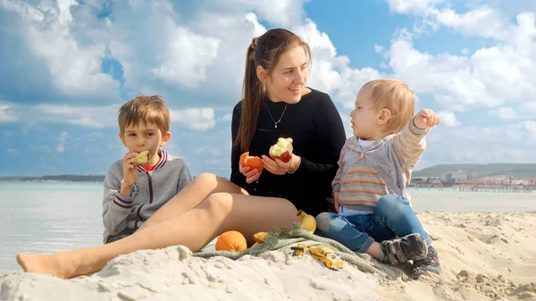 Szczęśliwa Kobieta Cieszy Się Piknikiem Plaży Dwoma Synami Jedząc Świeże — Zdjęcie stockowe