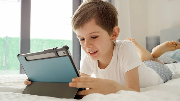 小男孩躺在床上 带着一台平板电脑 使用小工具的儿童 教育和发展 — 图库照片