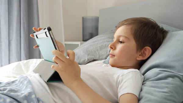 Jeune Garçon Joyeux Joue Avec Une Tablette Pendant Est Couché — Photo