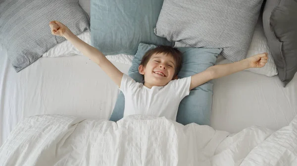 Rapaz Sorridente Feliz Abre Cobertor Estende Mãos Cama — Fotografia de Stock