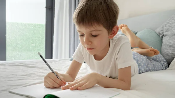 Retrato Niñito Trabajando Tarea Cama Escribiendo Cuaderno Con Concentración Importancia — Foto de Stock