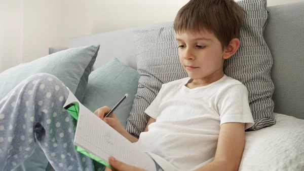 Niño Escribiendo Cuaderno Mientras Está Acostado Cama Esencia Educación Desarrollo —  Fotos de Stock