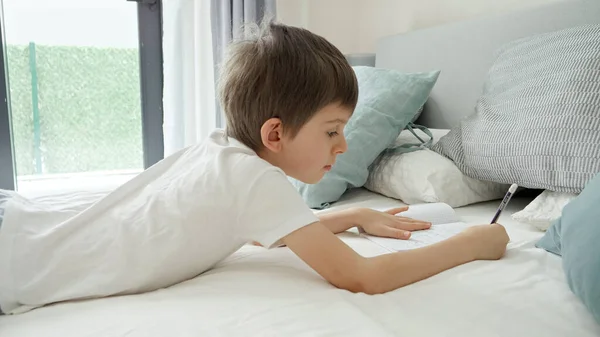 可爱的男孩早上醒来后躺在床上做作业 儿童发展和家庭远程教育的概念 — 图库照片