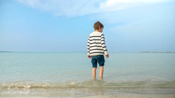 Widok Małego Chłopca Swetrze Spacerującego Piaszczystej Plaży Wchodzącego Wody Morskiej — Zdjęcie stockowe